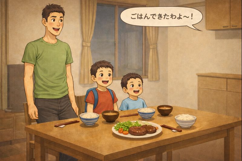 ダイニングテーブルの前に、細身で背の高いお父さんと、小学3年生と小学1年生の二人の息子が集まってきているイラスト。テーブルの上には、ご飯、味噌汁、サラダ、箸、ハンバーグが盛られた皿が並んでいる。キッチンの方からは、お母さんの「ごはんできたわよ～！」という声が聞こえてくるような、夕食前の温かい家庭のひとときが描かれている。